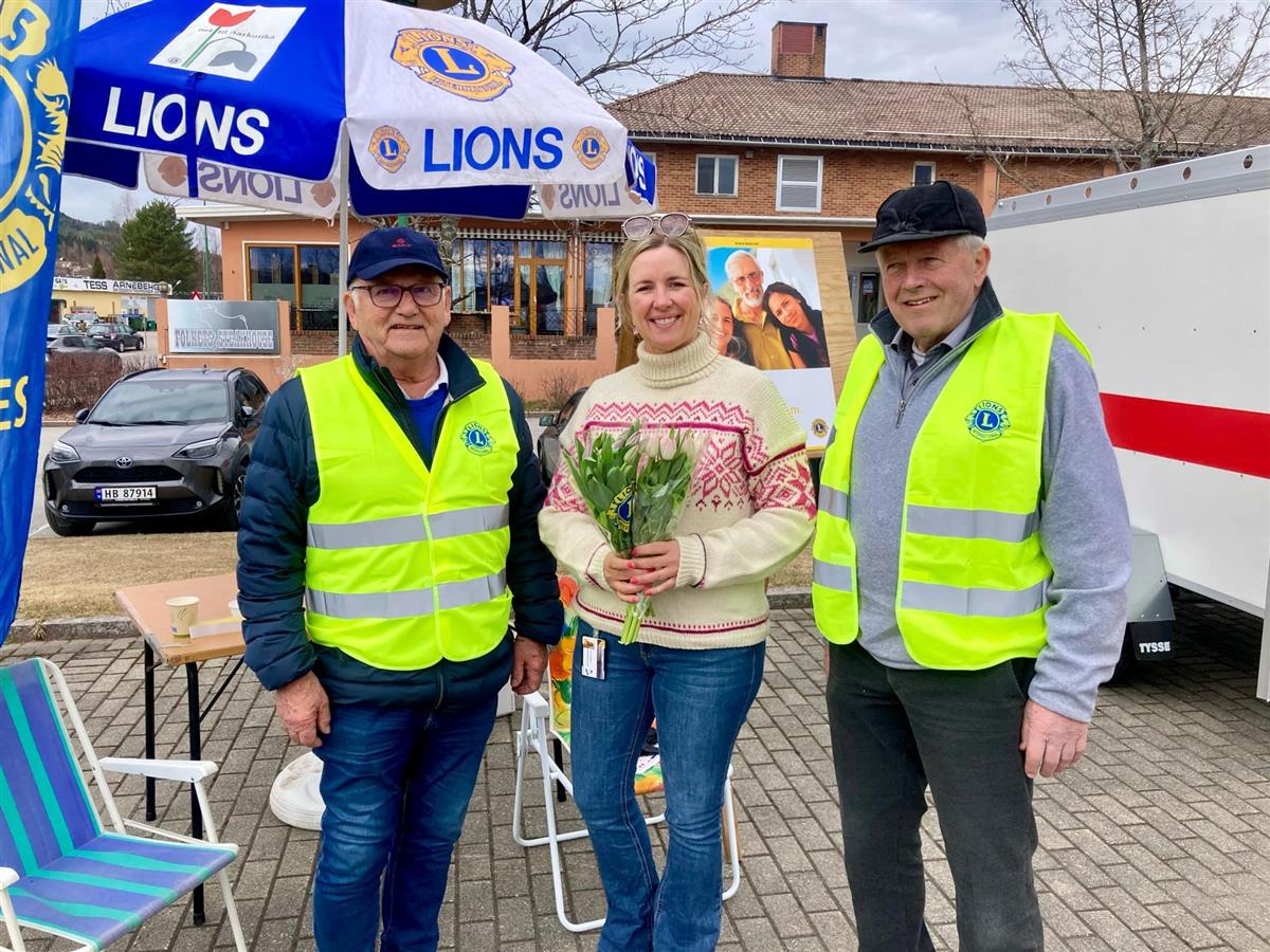 Tre personer foran parasoll merket med "Lions". - Klikk for stort bilde