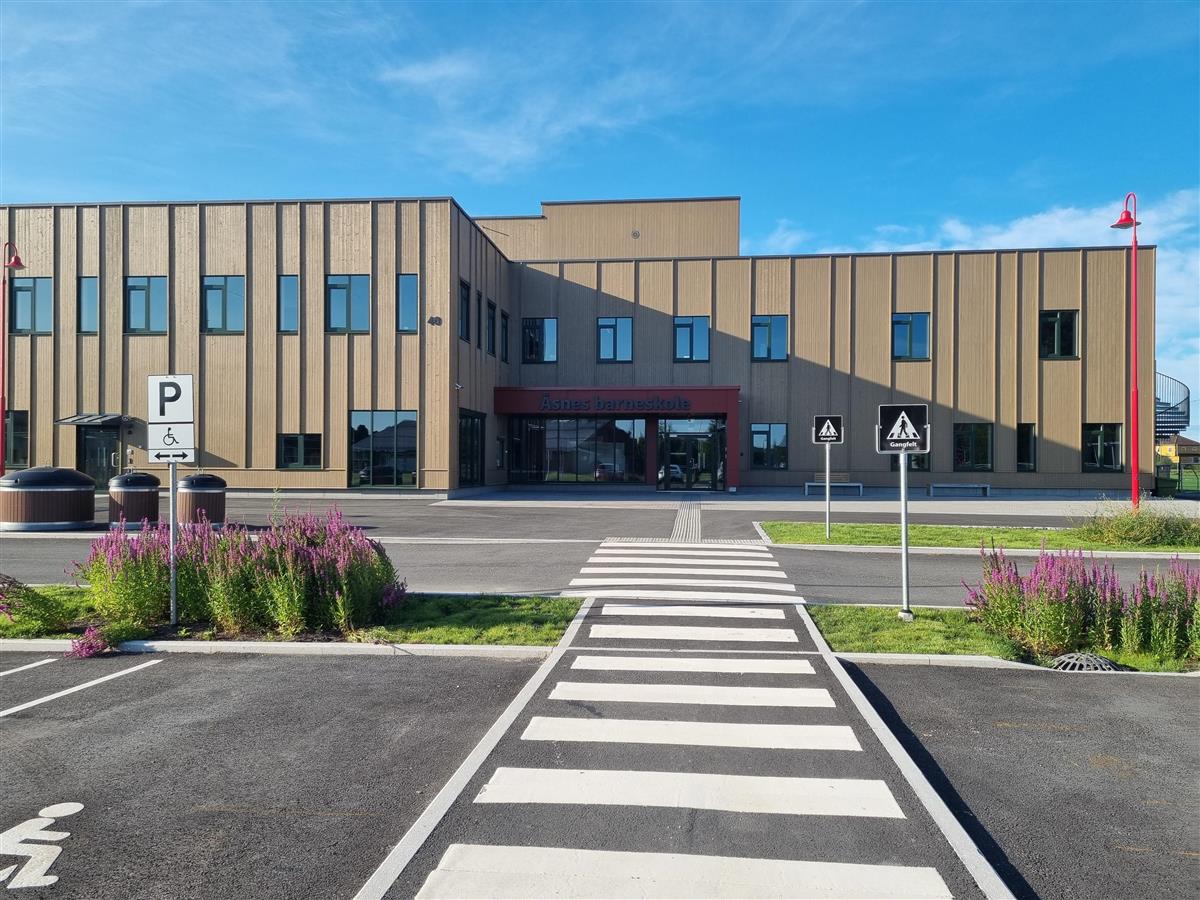 Hovedinngangen ved Åsnes barneskole. Bygning med vinduer og dører. Gangveg foran bygningen. - Klikk for stort bilde